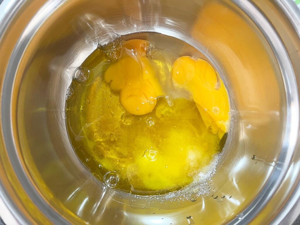 Wet ingredients for cream cheese brownies in a metal mixing bowl.