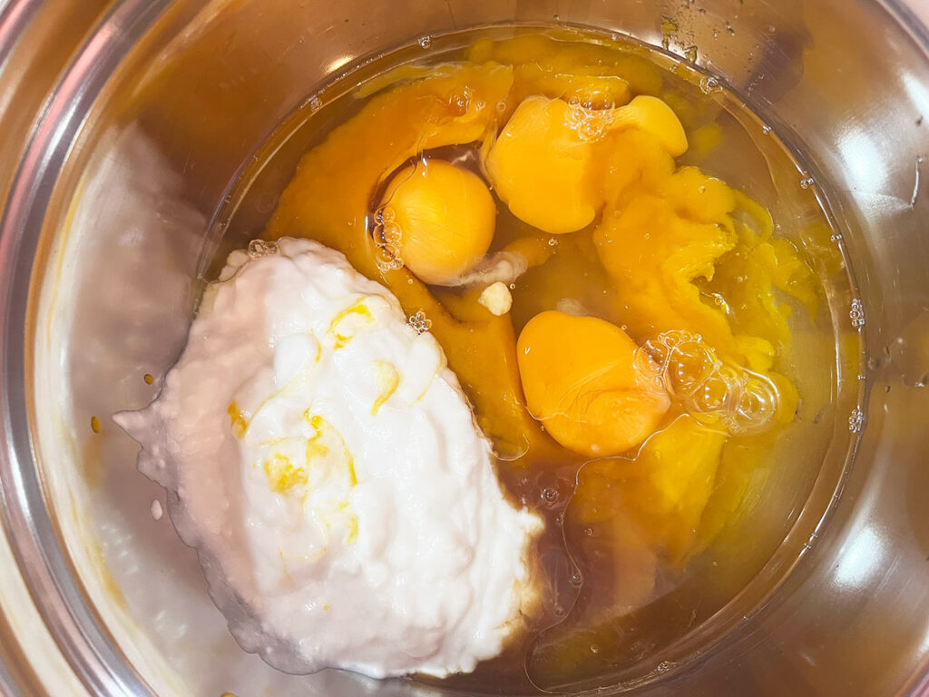 Wet ingredients for pumpkin bars in a mixing bowl, unmixed.