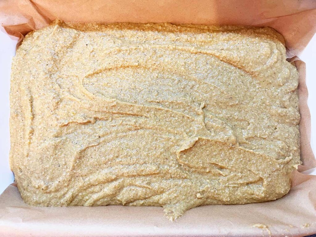 Pumpkin bar batter poured into a parchment-lined baking dish.