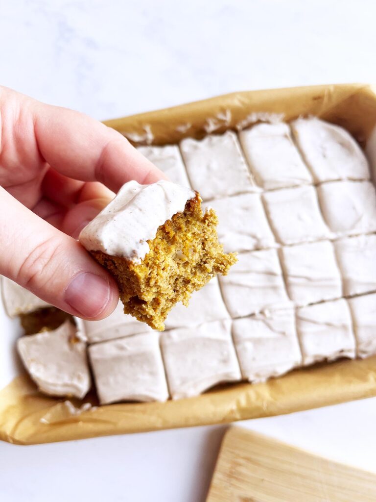 Overhead focus. A hand holds a bitten pumpkin bar.
