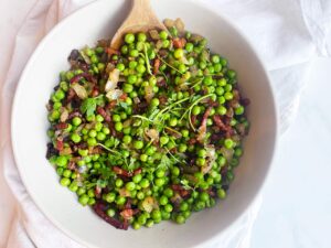 Overhead focus. A white bowl filled with Pea Salad.