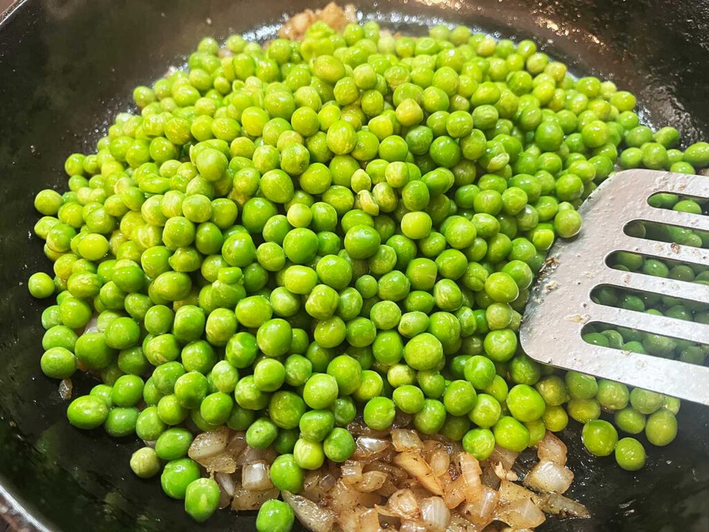 Thawed peas adde to the skillet with onions and garlic.
