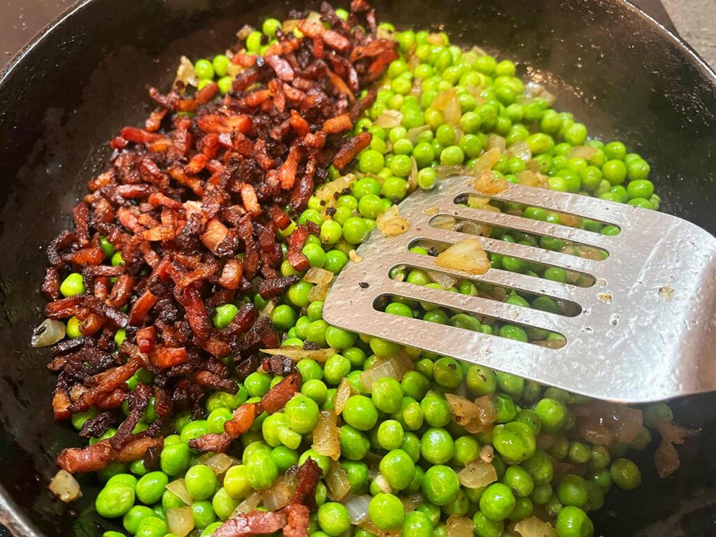 Adding the cooked bacon to the skillet.