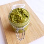 Slight overhead view of an open, glass jar filled with pistachio pesto.