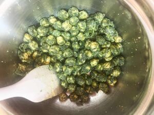 Chickpeas mixed with seasoning in a mixing bowl.