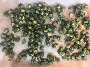 Seasoned chickpeas poured out onto a parchment-lined baking sheet for baking.