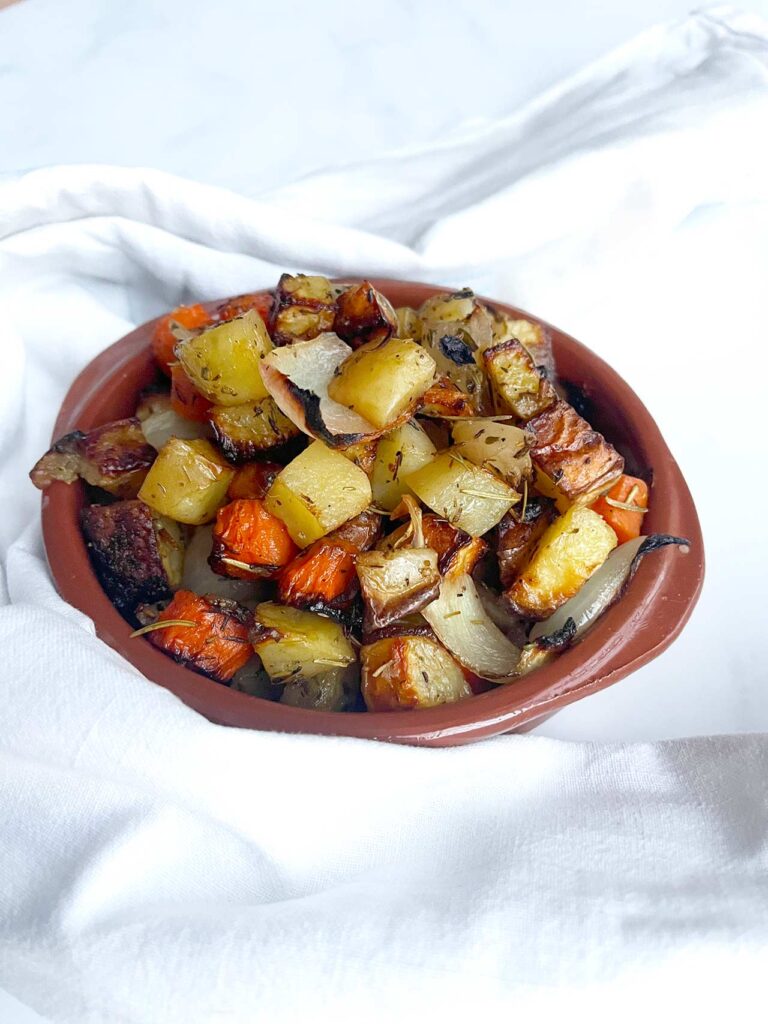 Front view of a brown bowl filled with sheet pan roasted vegetables.