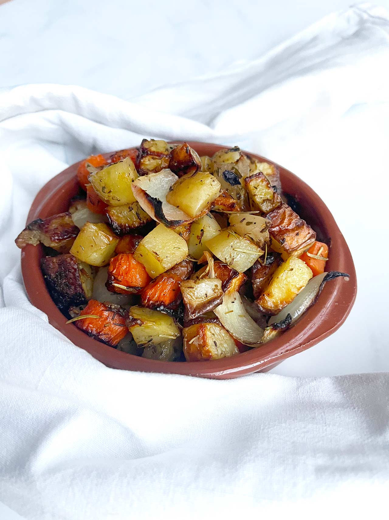 Front view of a brown bowl filled with sheet pan roasted vegetables.