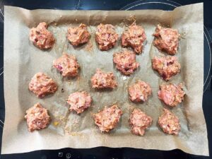 Overhead focus. Smokey Pumpkin Turkey Meatballs mix rolled into meatballs and placed on a parchment-lined baking pan.