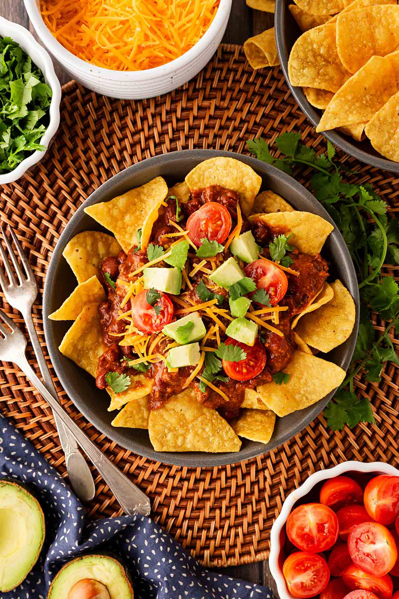 Overhead focus. A bowl on a table place setting, filled with chili nachos.