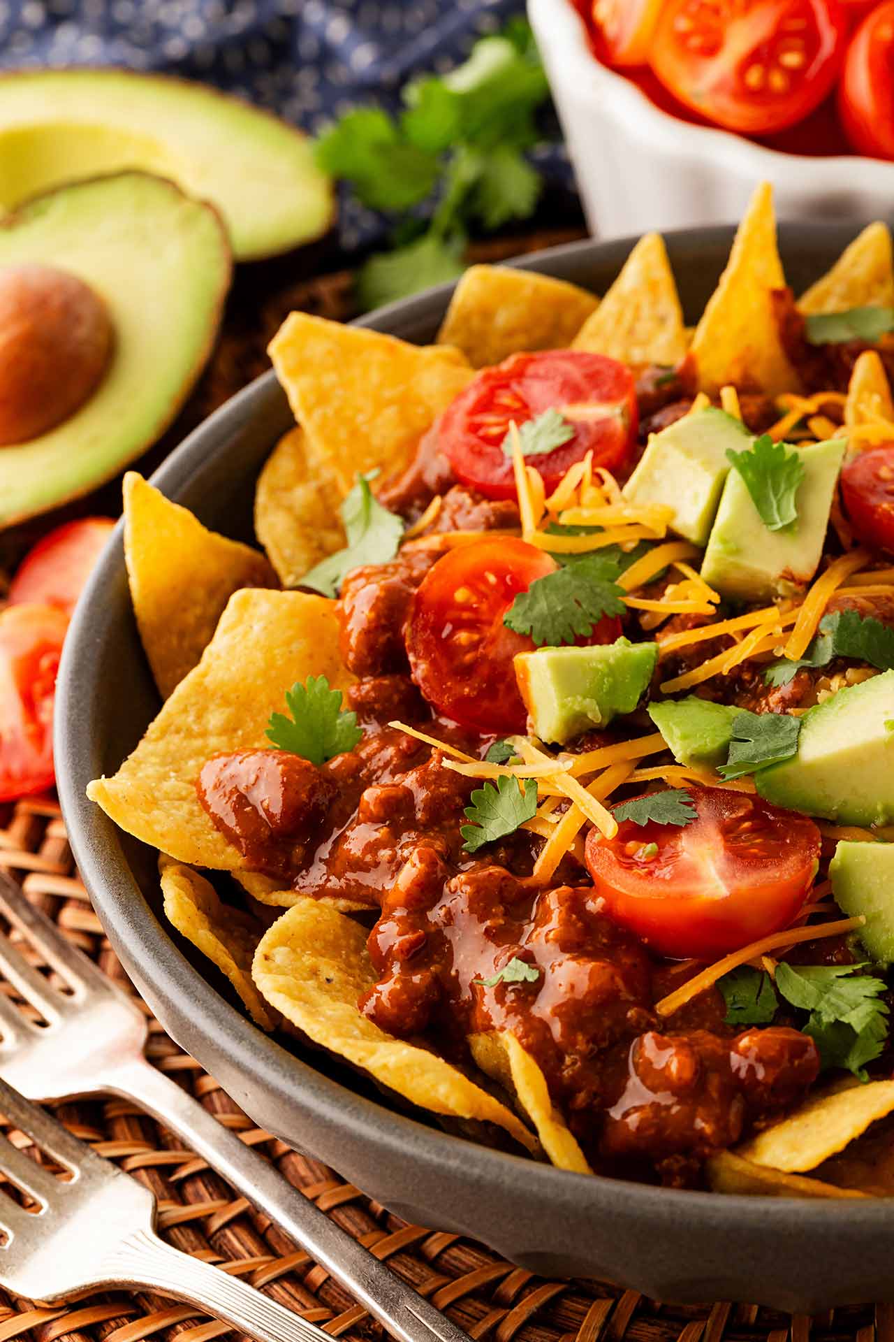 Closeup and partial view of a bowl of chili nachos.