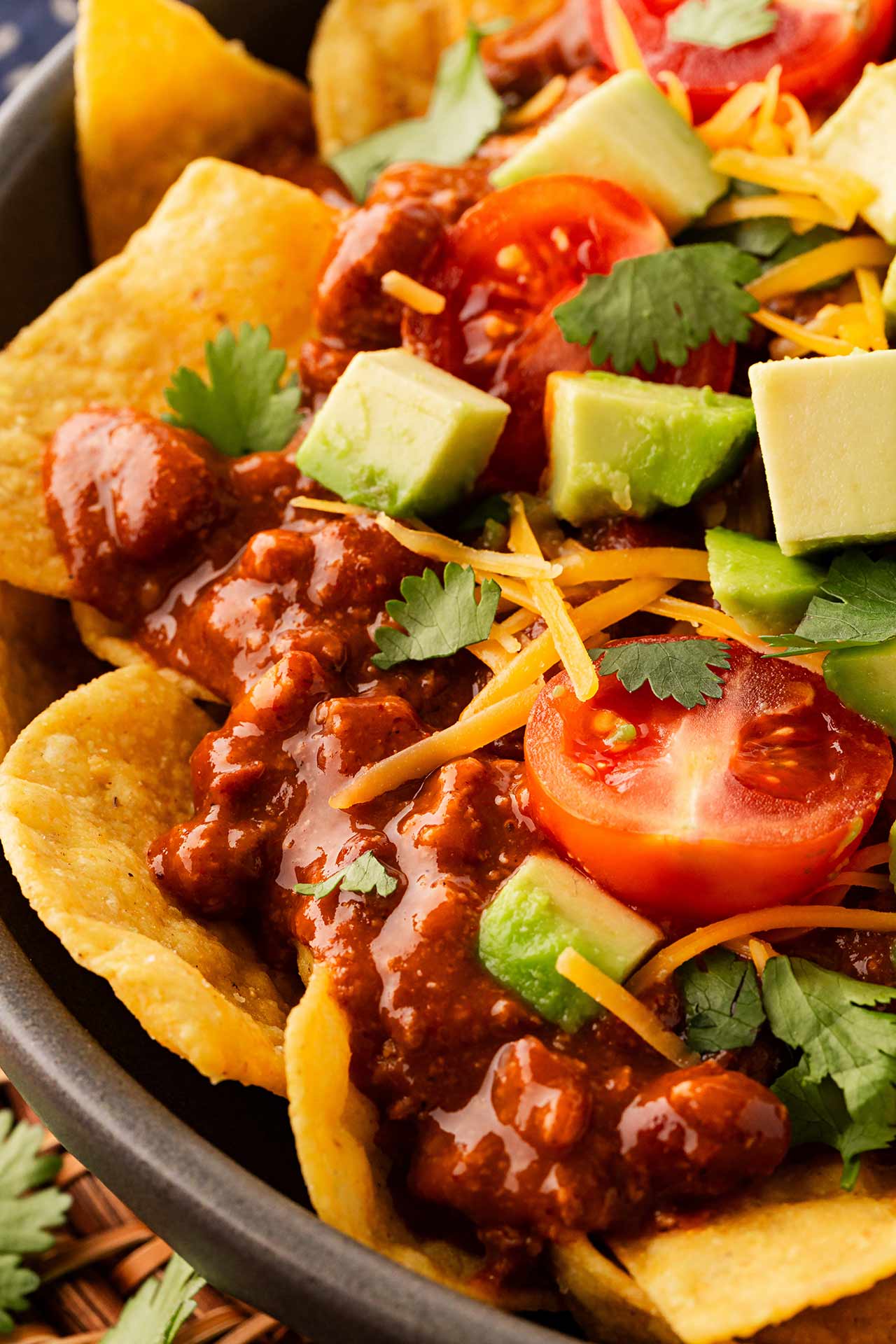 Closeup partial view of a bowl of chili nachos.