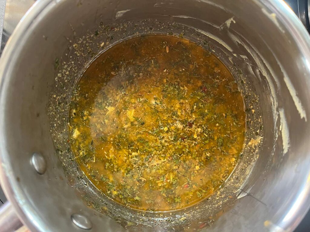 Overhead focus. Melted butter with herbs in a pot.