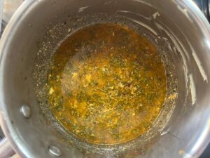 Overhead focus. Melted butter with herbs in a pot.