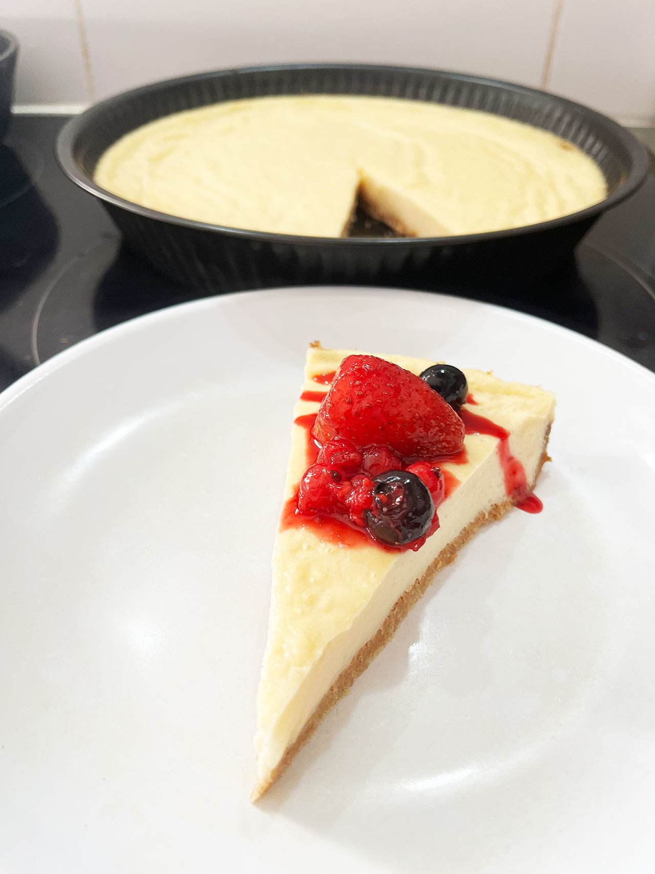Front focus of a slice of Custard Pie on a white plate. The pie pan sits behind it.