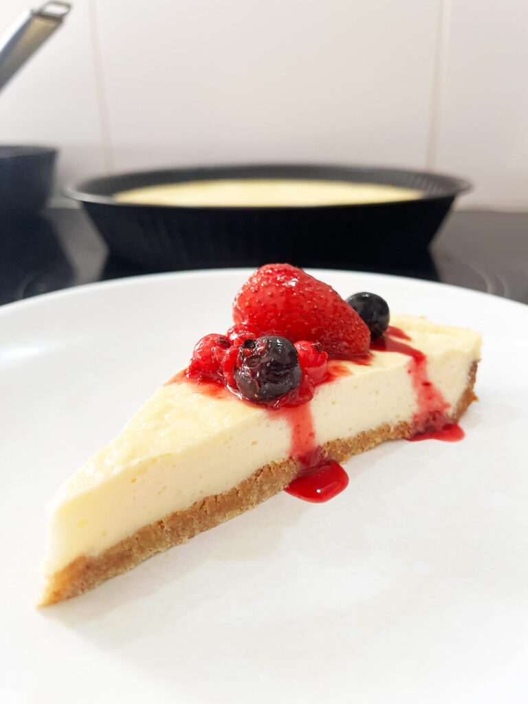 Eye level focus. A slice of Custard Pie on a white plate with berries and sauce on it.
