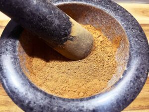 Closeup of a mortar and pestle. The mortar is filled with gingerbread spice.