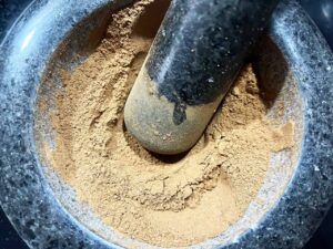 Gingerbread spice mixed together by a pestle in a mortar.