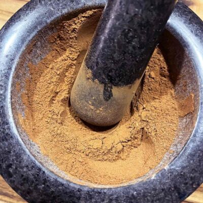 Overhead focus. A mortar filled with gingerbread spices. A pestle rests in the spices.
