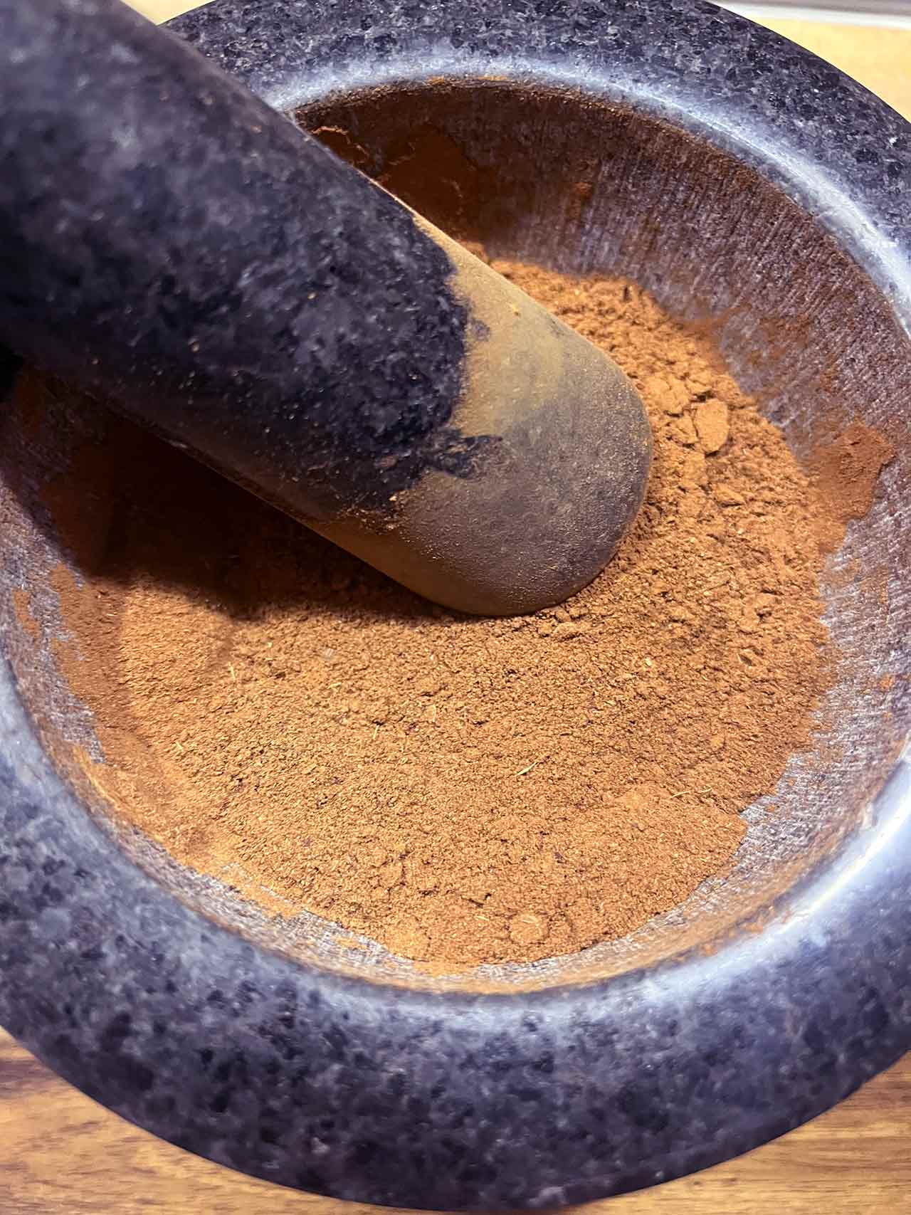 Overhead closeup of a mortar and pestle with gingerbread spice.