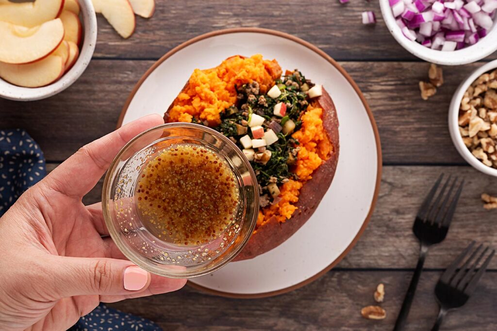 Pouring dressing over a Stuffed Sweet Potato.