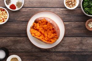 A baked sweet potato on a white plat, split open.