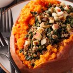 Front focus. A stuffed sweet potato with ground turkey and chopped apples on a white plate.