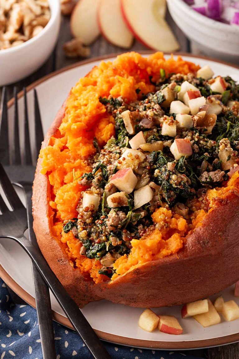 Front focus. A stuffed sweet potato with ground turkey and chopped apples on a white plate.