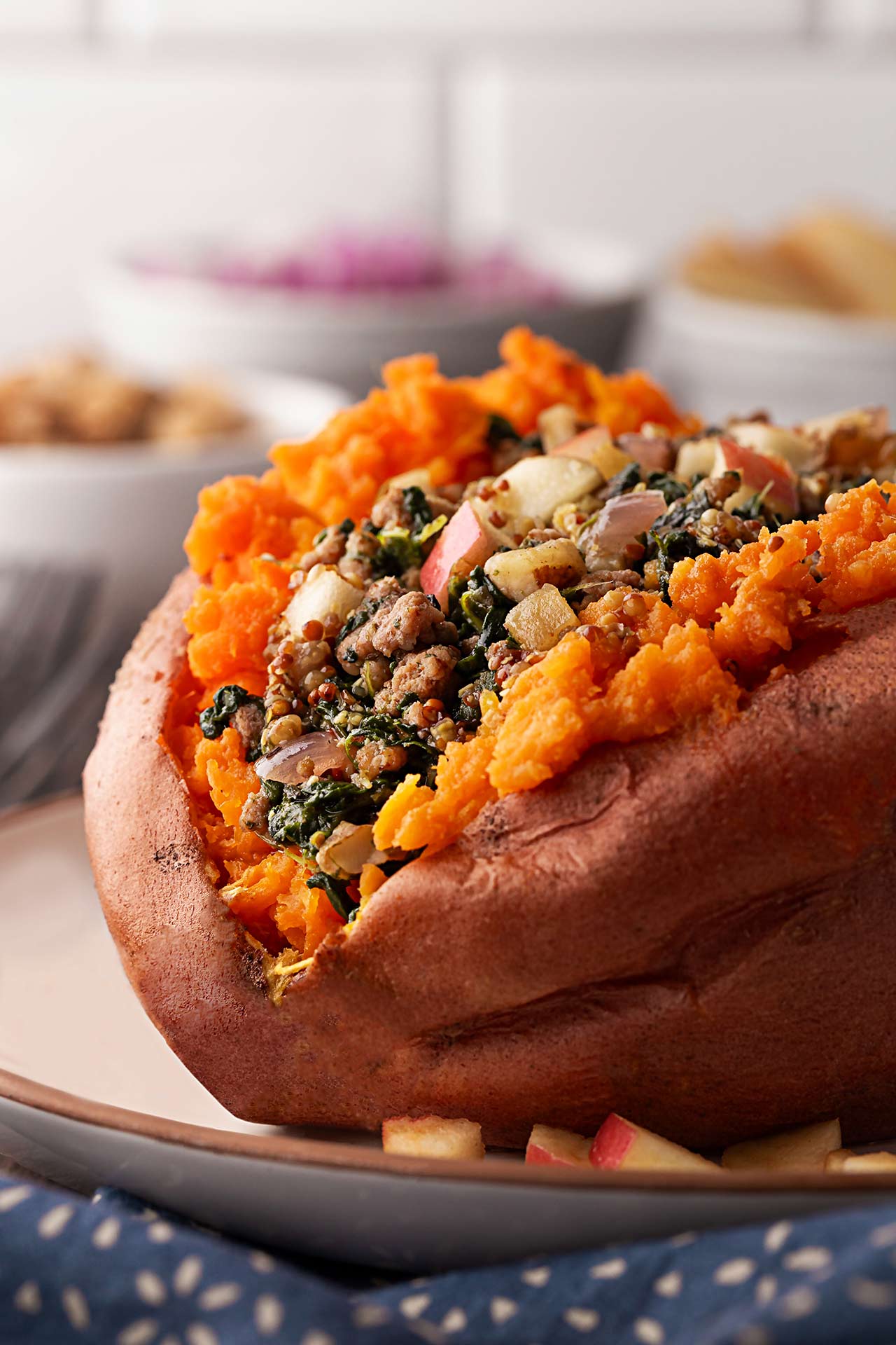 A Stuffed Sweet Potato piled with ground turkey, spinach, and chopped apples, on a white plate.