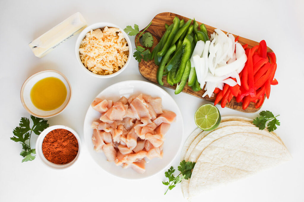 Overhead focus. Ingredients for Chicken Fajita Quesadillas prepped on a white surface.