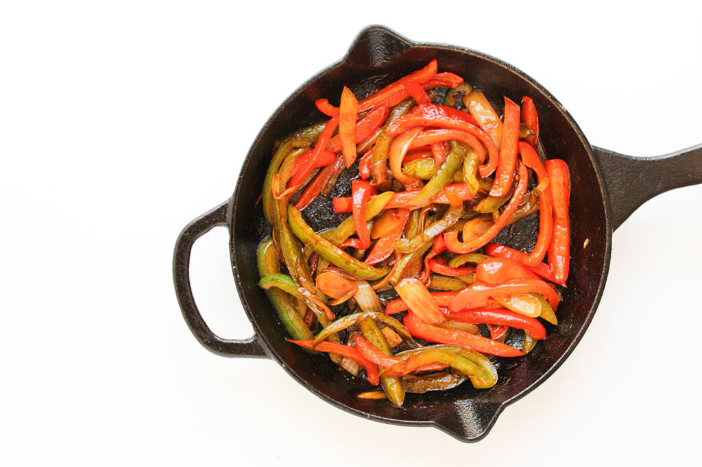 Peppers and onions cooked in a skillet.