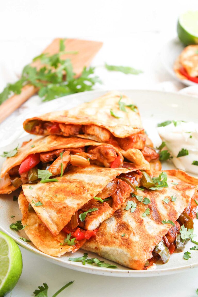Front focus. Four Chicken Fajita Quesadillas on a white plate.