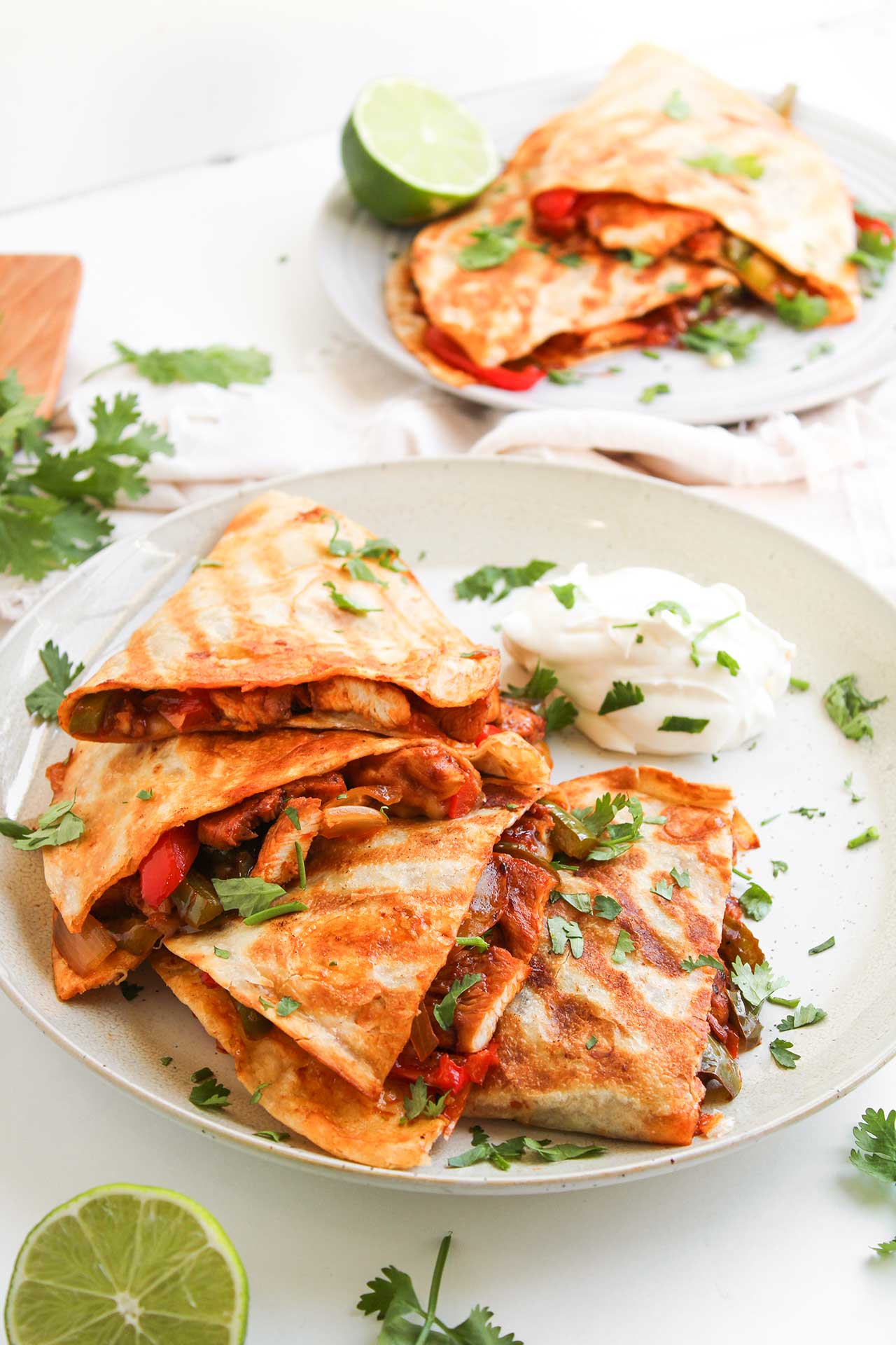 Semi overhead focus. Chicken Fajita Quesadillas on two white plates.