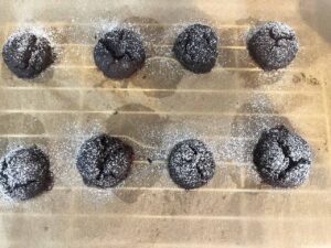 Baked Oat Flour Chocolate Crinkle Cookies cooling on a cooling rack, sprinkled with extra powdered sweetener.