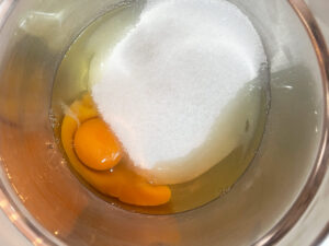 Eggs and sugar in a mixing bowl.