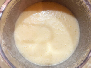 Eggs and sugar whisked together in a mixing bowl.