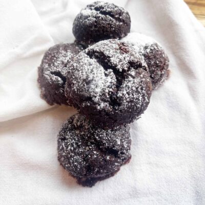 Overhead focus. A pile of Oat Flour Chocolate Crinkle Cookies on a white towel.