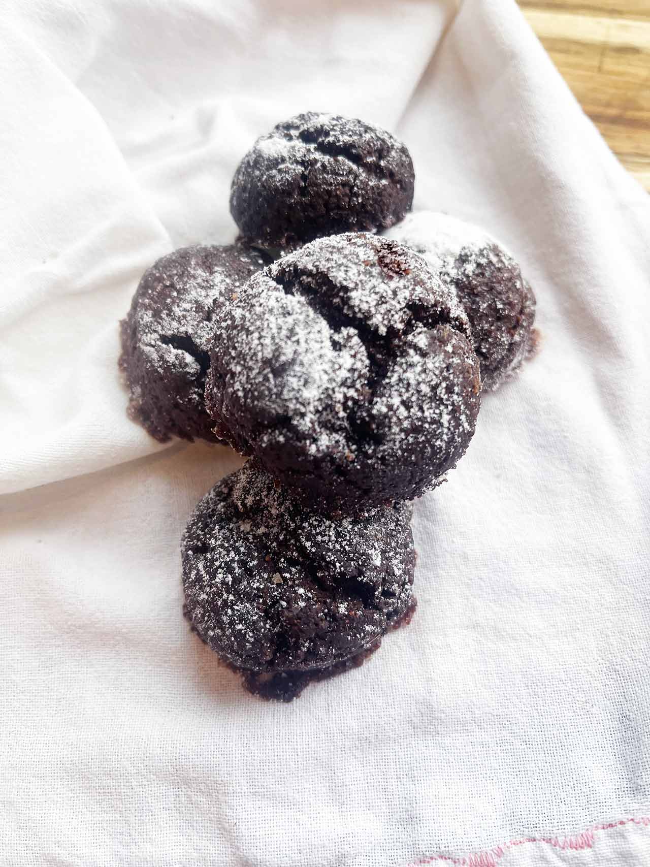 Overhead focus. A pile of Oat Flour Chocolate Crinkle Cookies on a white towel.