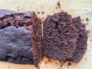 Overhead focus. A loaf of Chocolate Zucchini Bread on a cutting board with two slices cut and laying in front of the loaf.