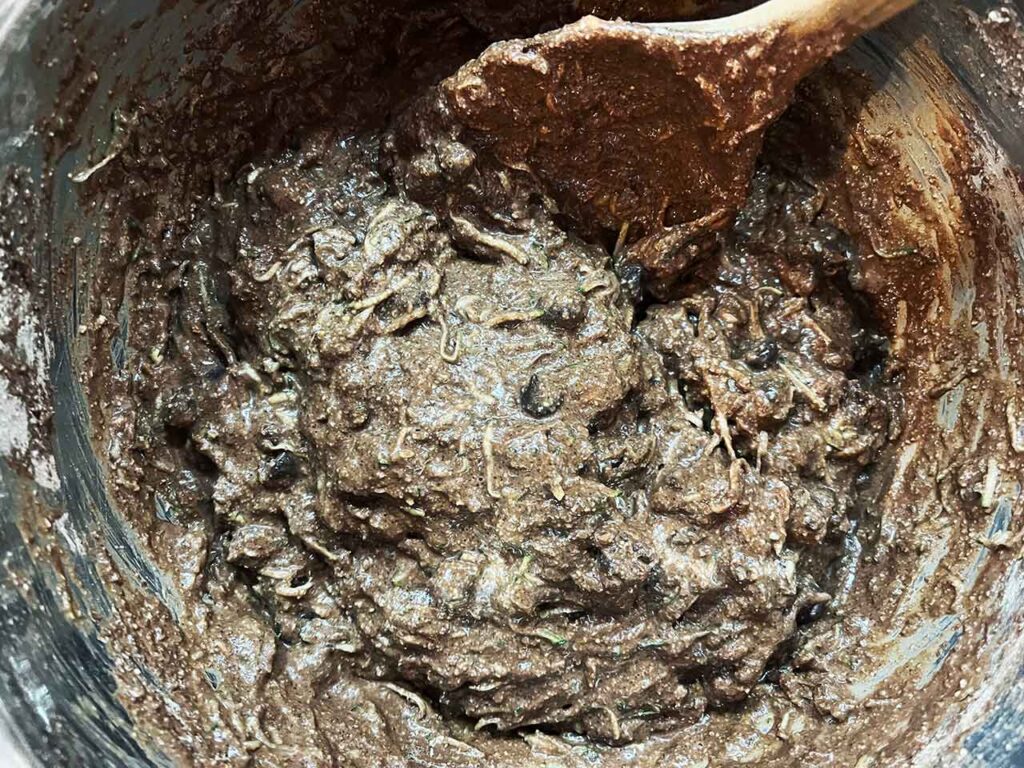 Mixed batter for Chocolate Zucchini Bread in a mixing bowl with a wooden spoon.
