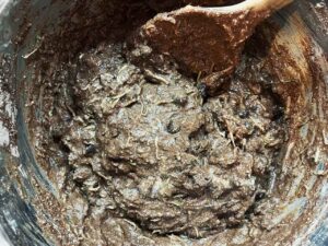 Mixed batter for Chocolate Zucchini Bread in a mixing bowl with a wooden spoon.