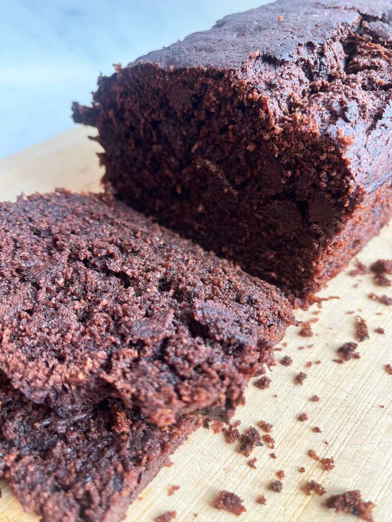 Side front focus. A sliced loaf of Chocolate Zucchini Bread on a cutting board.