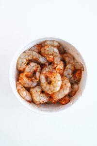 Seasoned shrimp in a white bowl.