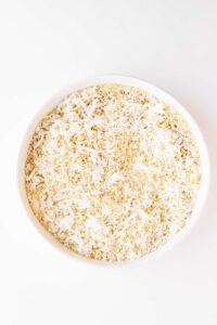 Overhead focus. A white bowl of mixed coconut and bread crumbs.
