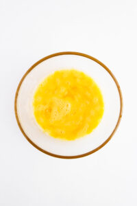 Overhead focus. A bowl of beaten egg. White background.