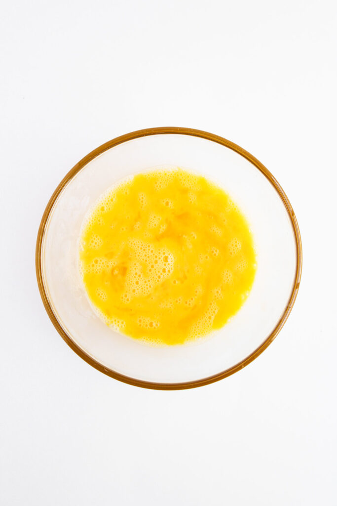 Overhead focus. A bowl of beaten egg. White background.