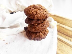 A stack of four Oat Flour Ginger Molasses Cookies on a white towel.