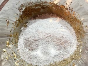 Dry ingredients added to wet ingredients in a mixing bowl.