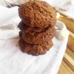 Front view. A stack of Oat Flour Ginger Molasses Cookies on a white towel.