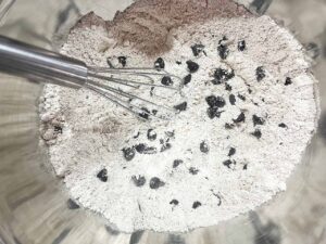 Chocolate chips whisked into a flour mix in a mixing bowl.